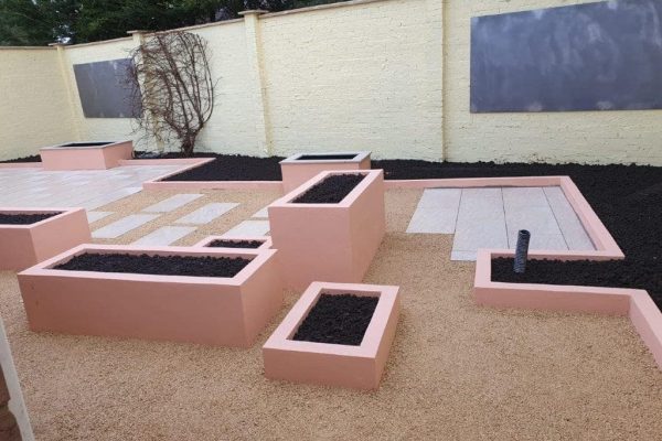 Pink rendered planters set into gravel and paving