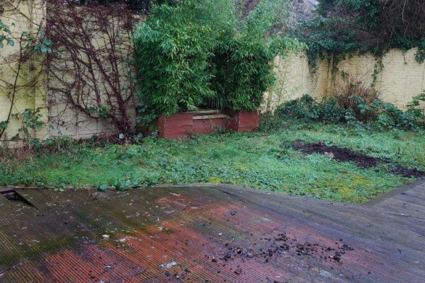 The courtyard before work began, with old decking and lawn