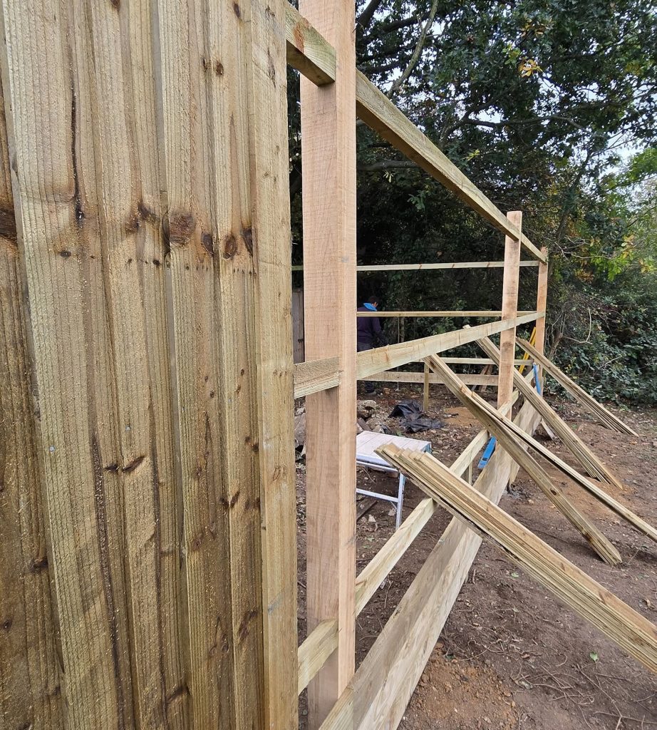 Feather edge boards being fixed to oak posts and cant rails