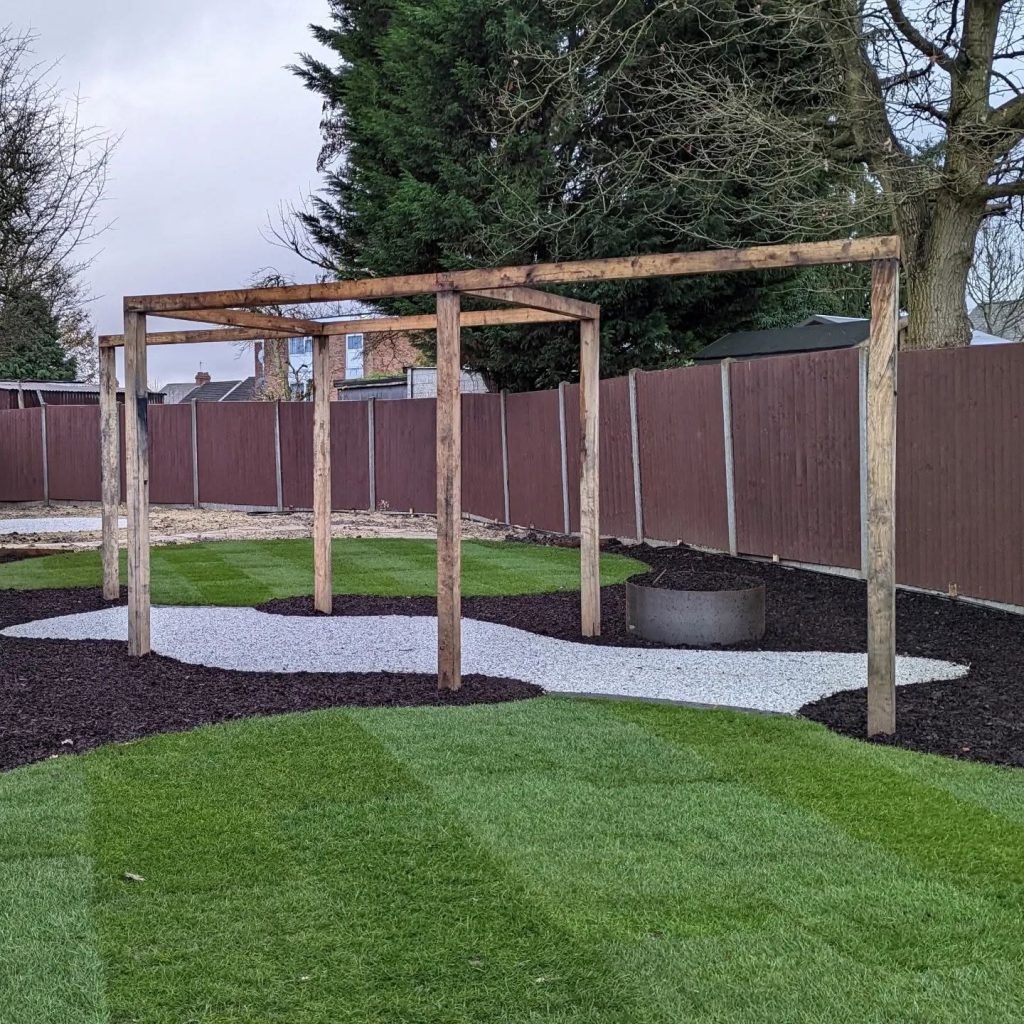 Green oak pergola set in white gravel beside a new lawn